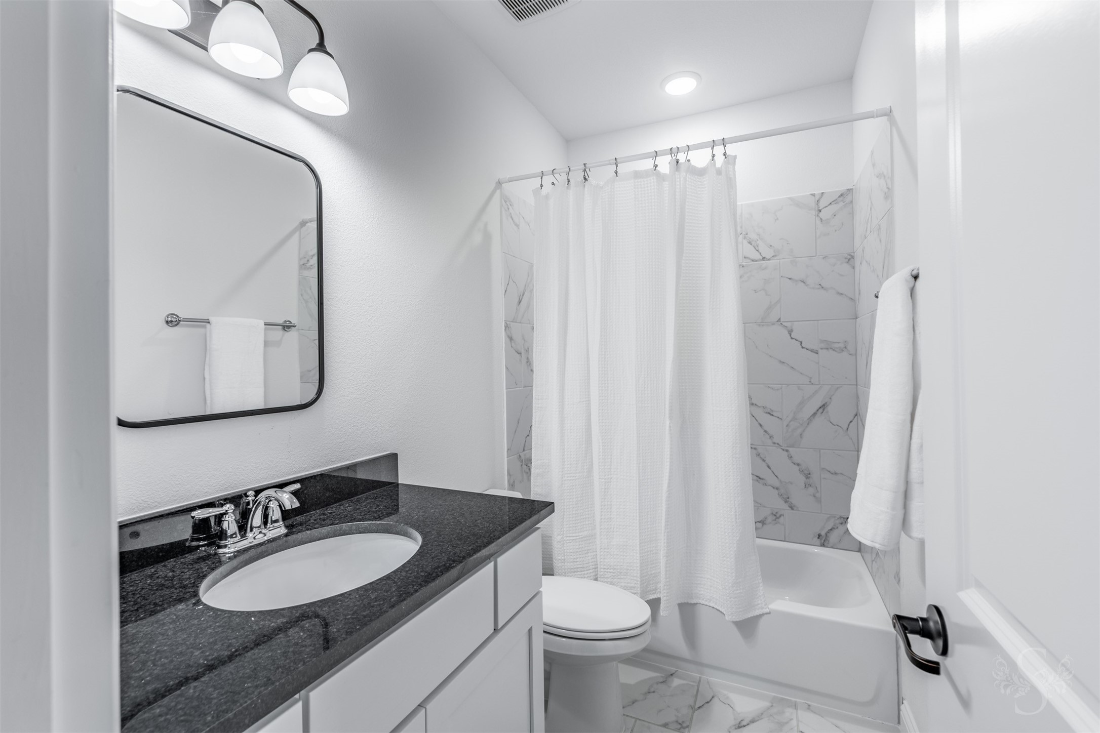 27919 Indigo Ridge Drive Fulshear, TX 77441 - Photo 41 of 50 A beautiful granite countertop and framed mirror bring a refined touch to this well-appointed secondary bath. The marble-look tub/shower surround and crisp tile flooring offer durability and style for everyday comfort.