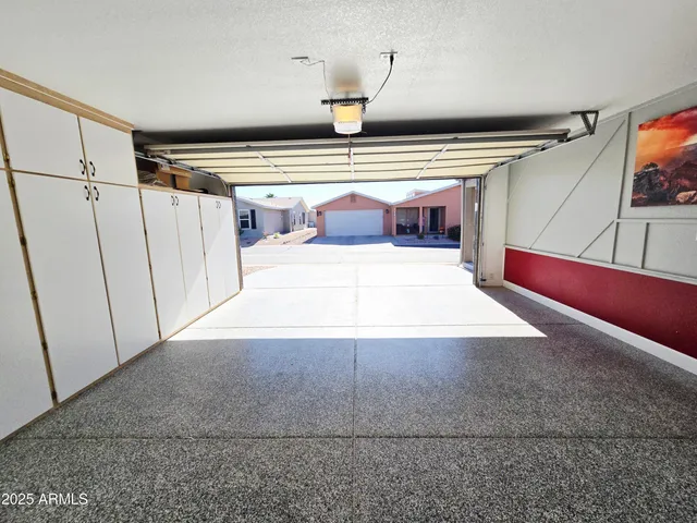 an empty room with wooden floor chandelier fan and windows