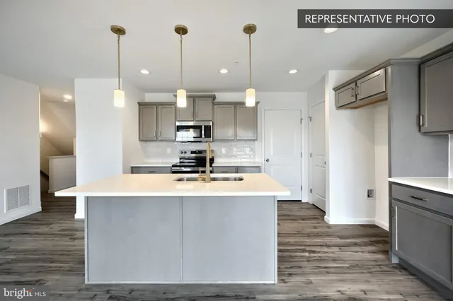 a large kitchen with kitchen island a stove a sink a refrigerator and a wooden floor