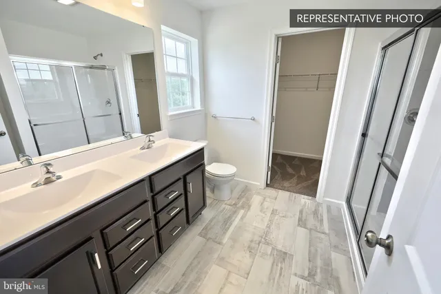 a bathroom with a sink a toilet a mirror and shower