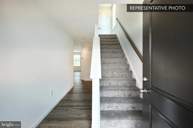a view of staircase with white walls and white door