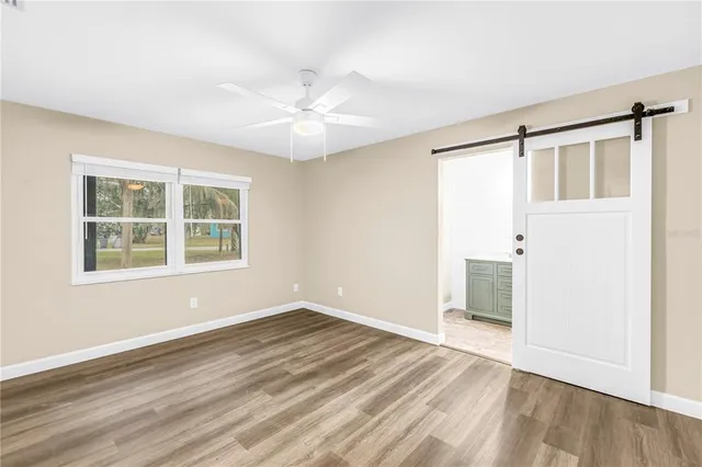 an empty room with wooden floor and fan
