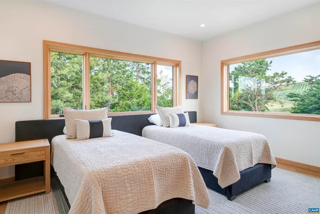 a bedroom with two beds and large windows