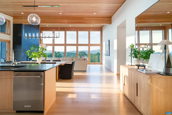 a living room with stainless steel appliances granite countertop a sink and a large window with wooden floor