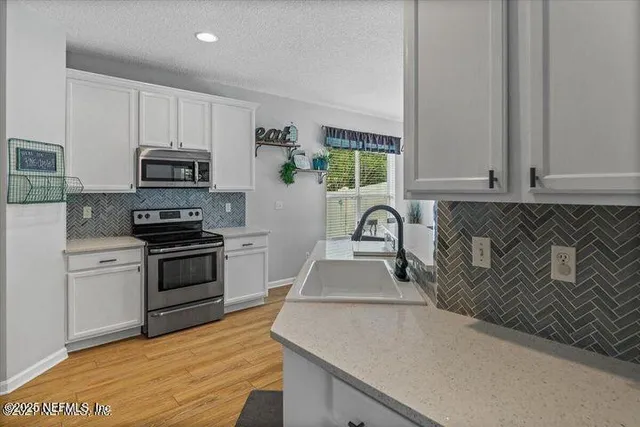 a kitchen with granite countertop a stove a sink and a microwave