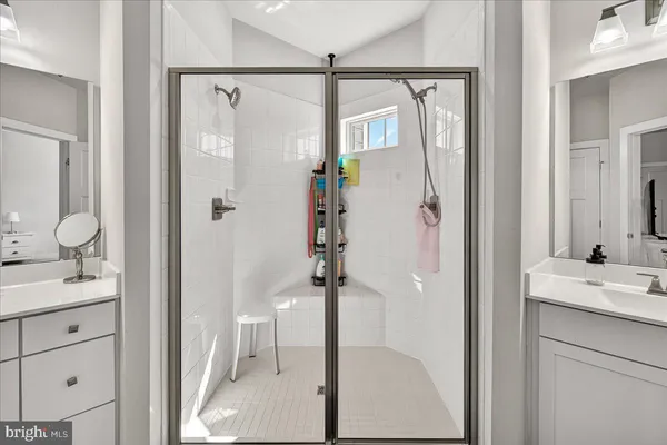 a bathroom with a granite countertop shower sink vanity and mirror