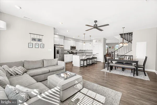 a living room with furniture kitchen view and a chandelier