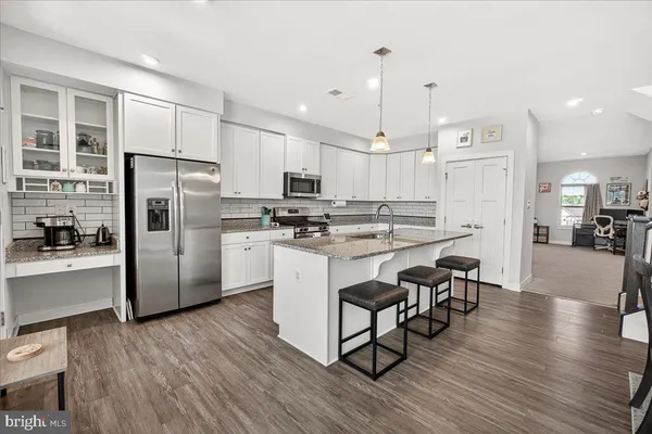 a kitchen with stainless steel appliances a refrigerator a stove a sink dishwasher and a refrigerator with wooden floor