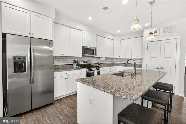 a kitchen with kitchen island granite countertop a sink a counter space appliances and cabinets