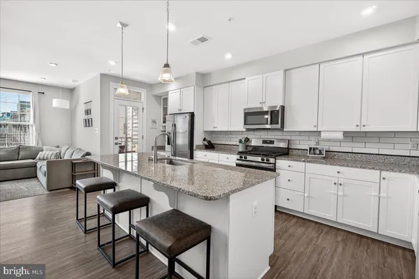 a large kitchen with stainless steel appliances granite countertop a stove a sink dishwasher a dining table and chairs with wooden floor