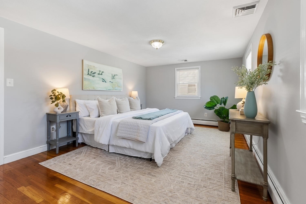 72 Grassland Street Lexington, MA 02421 - Photo 18 of 37 a bedroom with a bed a dresser and potted plants
