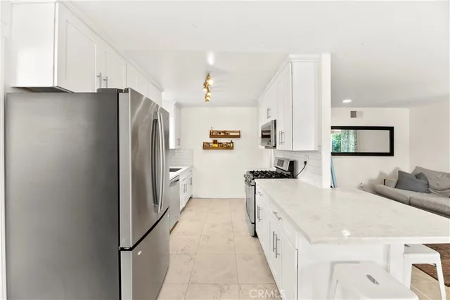 a kitchen with stainless steel appliances a stove and white cabinets
