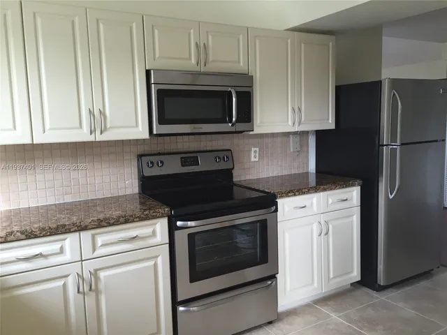 a kitchen with granite countertop white cabinets and stainless steel appliances