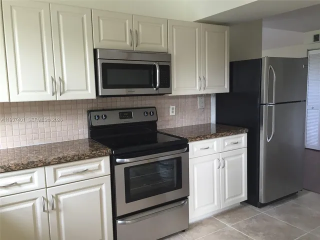 a kitchen with stainless steel appliances granite countertop white cabinets sink and a granite counter top
