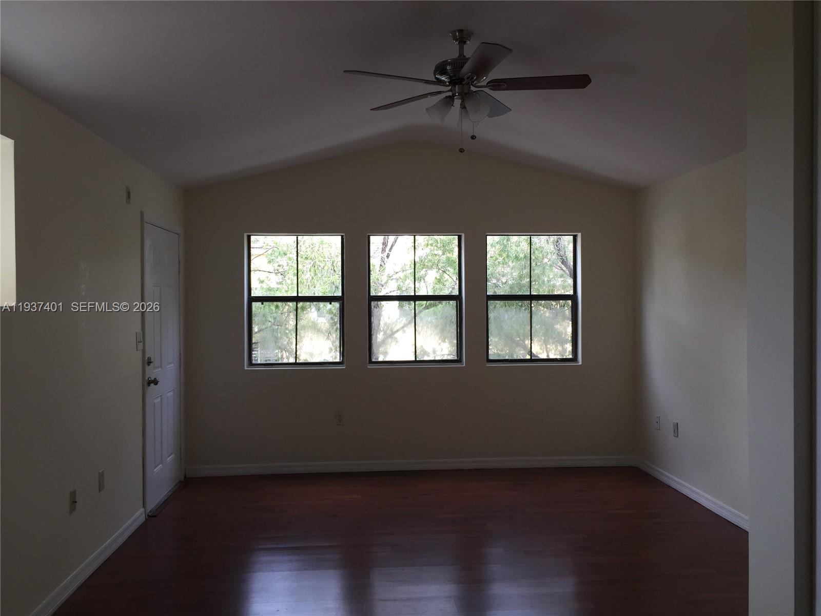10441 Southwest 156th Court, Unit 421 Miami, FL 33196 - Photo 5 of 36 an empty room with wooden floor fan and windows