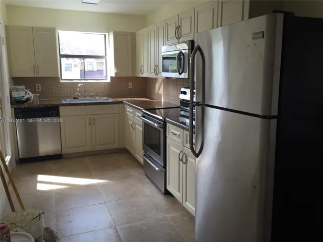 a kitchen with granite countertop a refrigerator and a sink