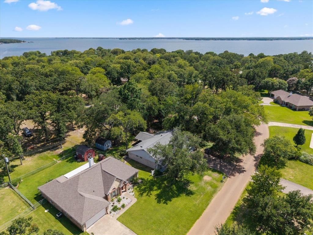 116 Meadowood Road Enchanted Oaks, TX 75156 - Photo 30 of 37 Aerial perspective showcasing a property surrounded by mature trees, with a large body of water visible in the distance