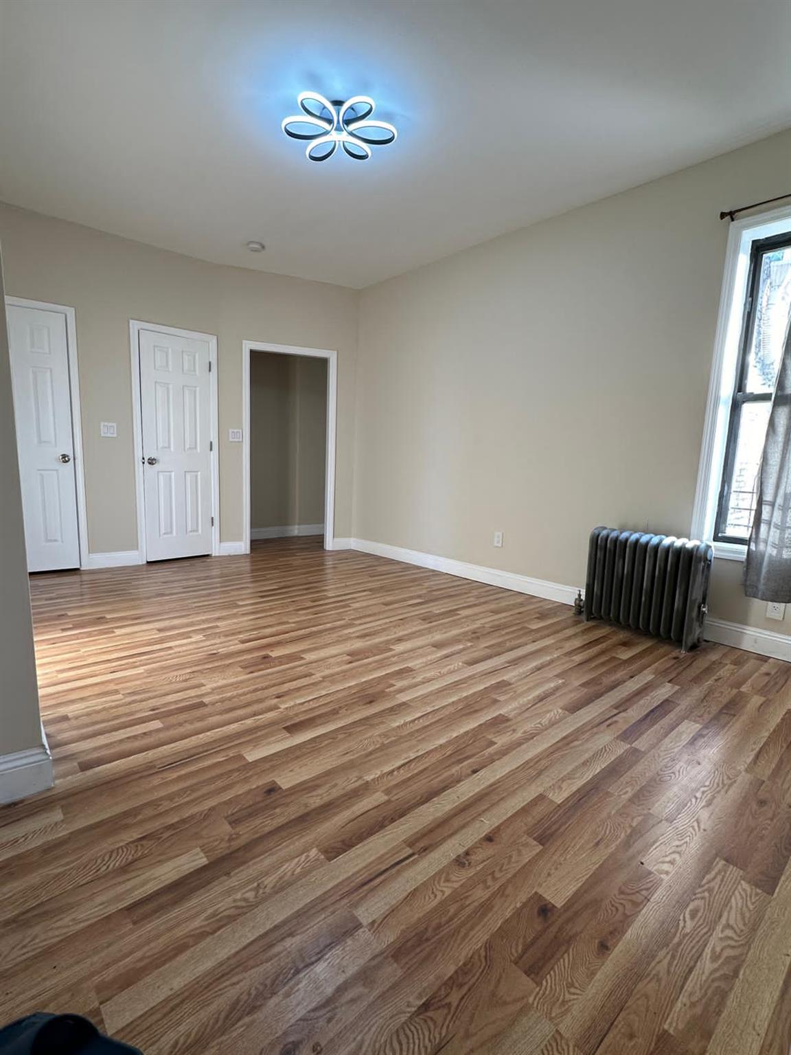 97-52 75th Street Queens, NY 11416 - Photo 5 of 9 a view of empty room with wooden floor and fan