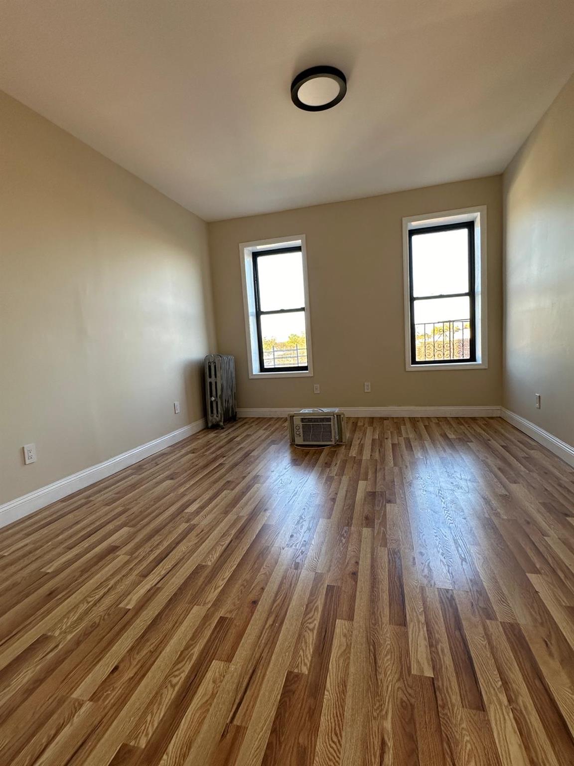 97-52 75th Street Queens, NY 11416 - Photo 7 of 9 an empty room with wooden floor and windows