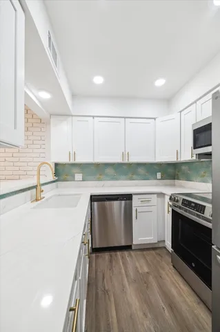 a kitchen with stainless steel appliances granite countertop a sink and a stove top oven with wooden floor