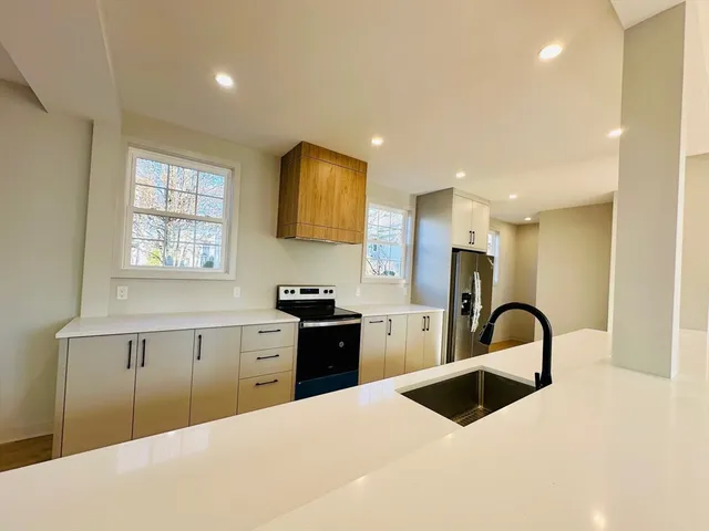 a kitchen with granite countertop a stove a sink a refrigerator and window