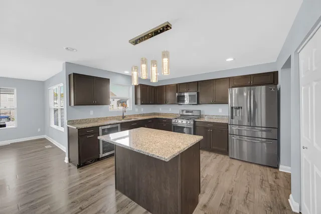 a kitchen with a refrigerator a sink and a stove top oven with wooden floor