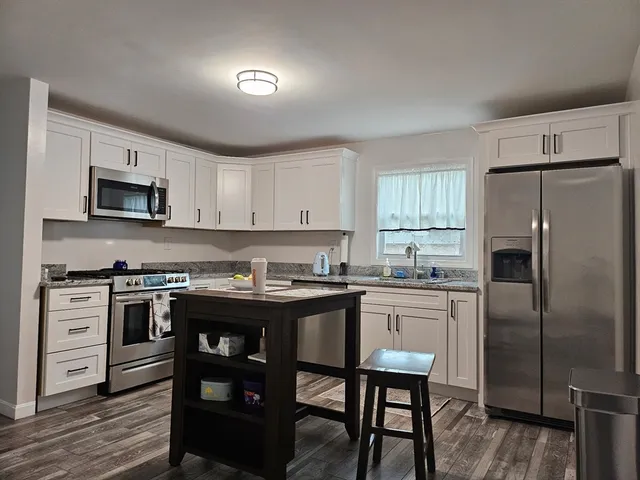 a kitchen with kitchen island white cabinets and stainless steel appliances