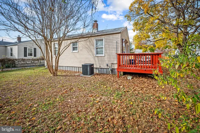 a view of a house with a yard and wooden bench