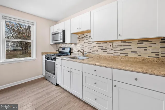 a kitchen with granite countertop white cabinets and stainless steel appliances