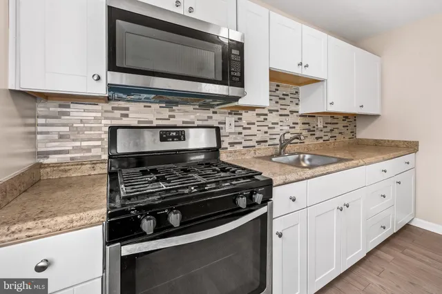 a kitchen with white cabinets and appliances