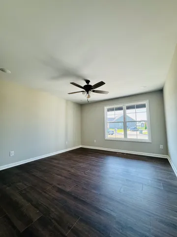 an empty room with wooden floor chandelier fan and windows