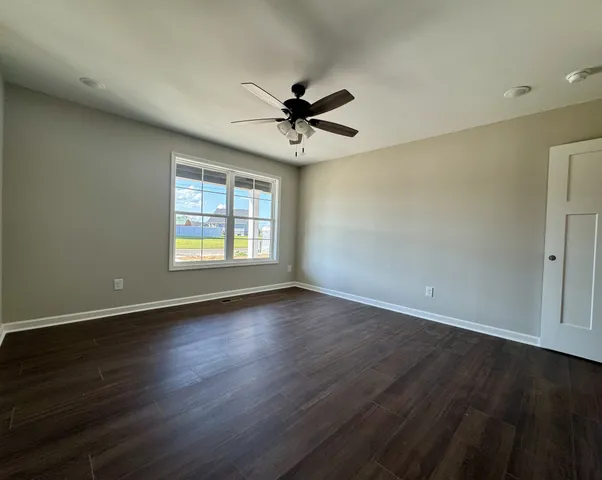 an empty room with wooden floor ceiling fan and windows