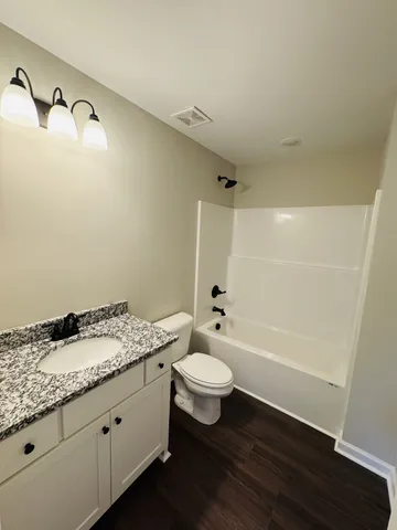 a bathroom with a granite countertop sink toilet and shower