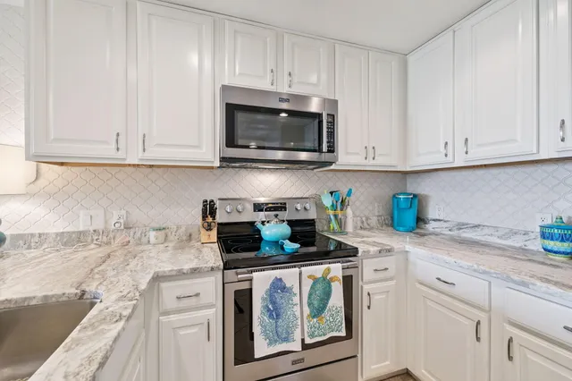 a kitchen with granite countertop white cabinets and stainless steel appliances