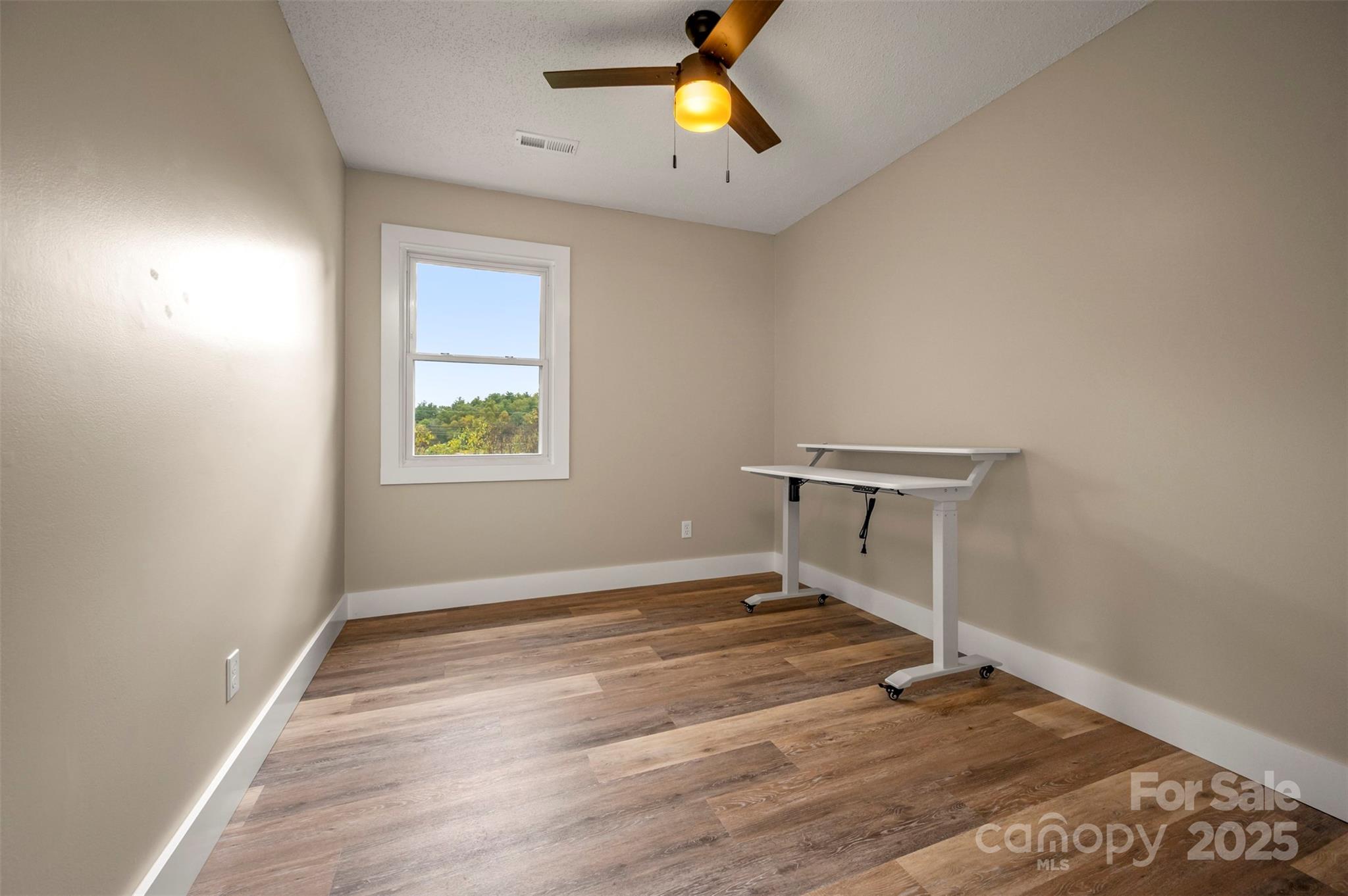 569 Lanning Road Hendersonville, NC 28792 - Photo 21 of 32 an empty room with wooden floor ceiling fan and windows