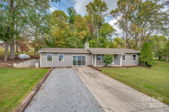 a view of house with a big yard and large trees