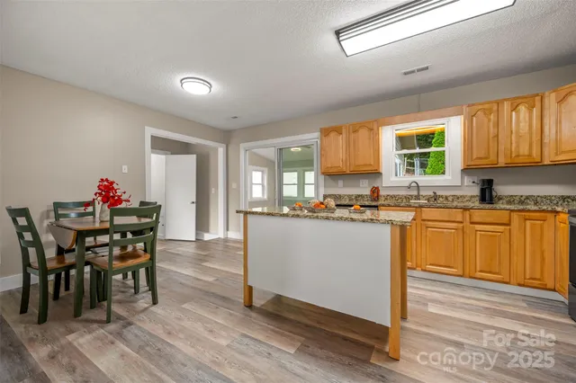 a kitchen with granite countertop wooden floor dining table and stainless steel appliances