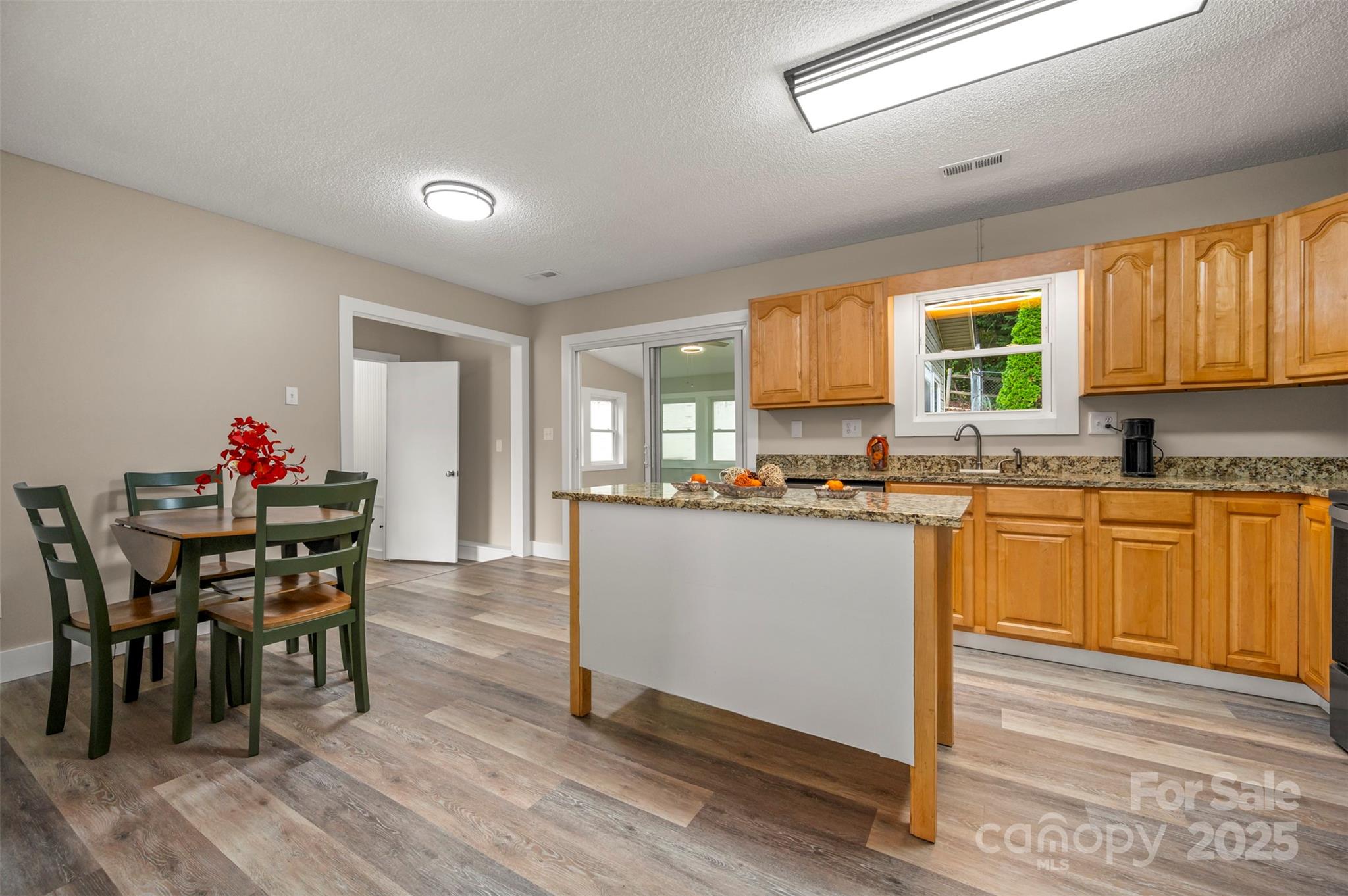 569 Lanning Road Hendersonville, NC 28792 - Photo 8 of 32 a kitchen with granite countertop wooden floor dining table and stainless steel appliances