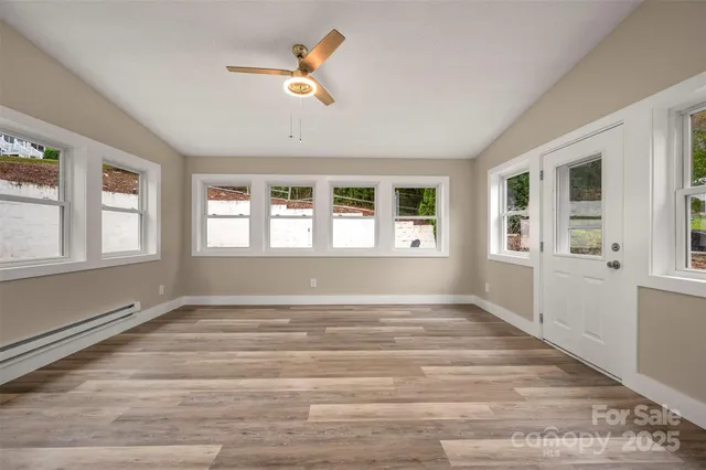 a view of an empty room with wooden floor and a window