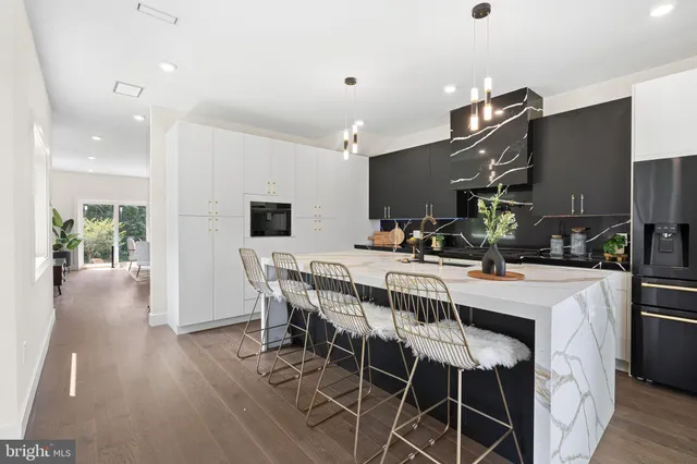a kitchen with stainless steel appliances a table chairs and wooden floor