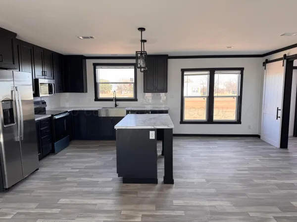 a kitchen with stainless steel appliances granite countertop a stove a sink dishwasher a refrigerator and a oven with wooden floor