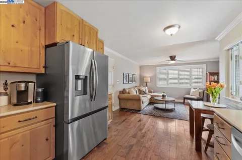 a kitchen with stainless steel appliances granite countertop a refrigerator a sink dishwasher a stove and white countertops with wooden floor