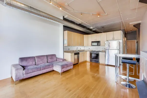 a living room with stainless steel appliances granite countertop lots of furniture and a kitchen view
