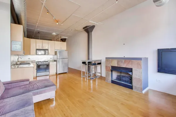 a living room with stainless steel appliances furniture a fireplace and a flat screen tv