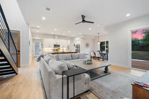 a living room with furniture kitchen view and a wooden floor