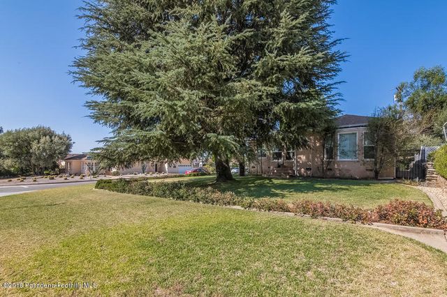 a view of a house with a big yard and large trees