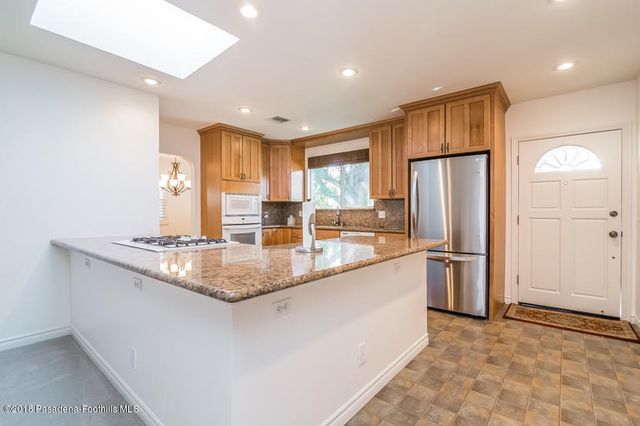 a kitchen with stainless steel appliances granite countertop a refrigerator a sink a stove a microwave and a refrigerator