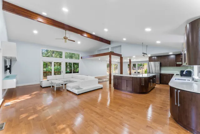 a large living room with stainless steel appliances kitchen island granite countertop furniture and a large window