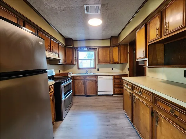 a kitchen with a sink cabinets stainless steel appliances and a window