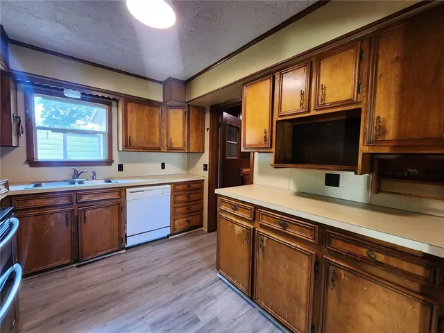 a kitchen with a sink wooden floor and stainless steel appliances